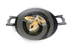 Hilsha or ilish fish frying on a cast iron pan.