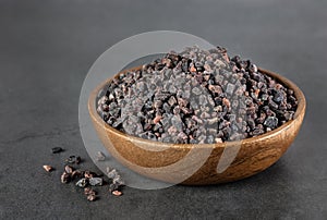 Himalayan black salt in a wooden bowl on a gray background. Spices background.