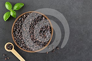 Himalayan black salt in a wooden bowl on a gray background. Spices background. Flatlay. Copy space.