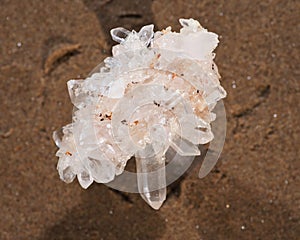 Himalayan clear quartz cluster with hematite inclusions on wet sand on the beach