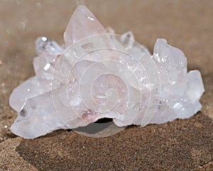 Himalayan clear quartz cluster with hematite inclusions on wet sand on the beach