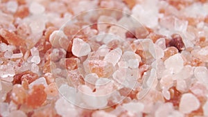 Himalayan coarse rock salt. Falling pink orange crystals in slow motion. Macro.