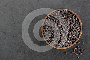 Himalayan crystal black salt in a wooden bowl on a gray background. Spices background. Flatley. Copy space.