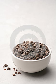 Himalayan or Indian black salt in ceramic bowl on grey concrete background