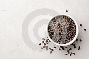 Himalayan or Indian black salt in ceramic bowl on grey concrete background