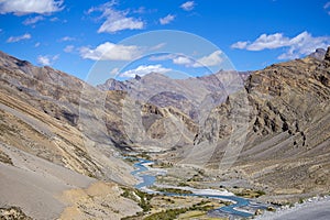 Himalayan landscape in Himalayas mountains along Manali - Leh highway. Ladakh, India. Big mountains, dirt road, blue sky, river an
