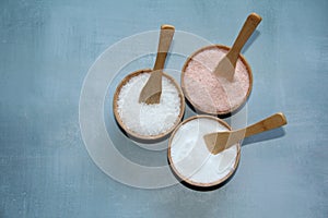 Himalayan pink salt, fine salt and coarse salt in crystal stones in wooden bowls