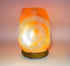 Himalayan pink salt lamp with orange red glow isolated on light background which can boost mood, improve sleep, ease allergies,