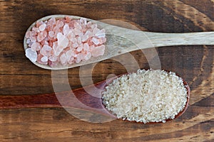 Himalayan pink salt and raw can sugar in wooden spoons.
