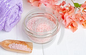 Himalayan pink spa salt in a glass bowl with bougainvillea flower and towel, massage and aromatherapy