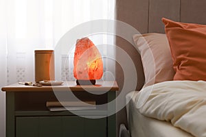 Himalayan salt lamp, air ionizer and accessories on nightstand in bedroom photo