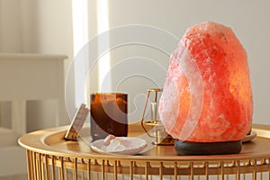 Himalayan salt lamp, candles and crystals on golden table indoors, space for text