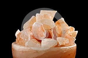 Himalayan salt lamp close up isolated on the dark background