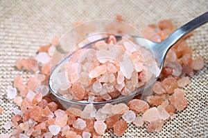 Himalayan salt with metal spoon on linen background