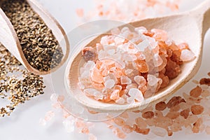 Himalayan salt and pepper on the wooden spoons and white table