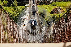 Trekkers and Sherpa crossing a suspension iron bridge in Everest base camp route.