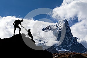 Teamwork couple hikers silhouette in mountains, climbers team