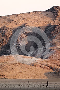 Himba woman walking in an arid landscape.