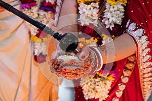 Hindu bride and groom held ghi in their hands, participating in the wedding ritual. Beautiful traditional Indian wedding ceremony