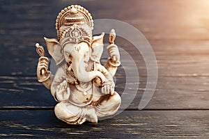 Hindu god Ganesh on black background. Statue on wooden table