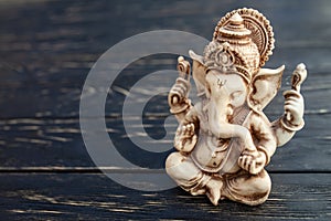 Hindu god Ganesh on black background. Statue on wooden table