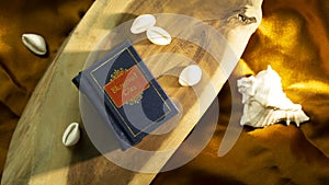 Hindu holy book and cowrie shell on a wooden surface with golden satin cloth