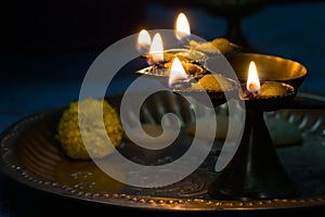 hindu puja essential panch pradeep or five headed oil lamp burning with glowing flame with marigold flowers kept on brass plate.