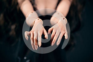 Hinged doll on a black background. Beautiful female hands closeup