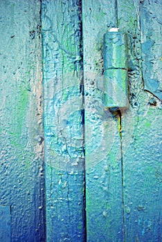 Hinges on old iron door with a shabby turquoise blue, green paint