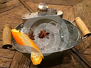 Hip screwdriver cocktail in the flask severing on the ice bucket decorate with orange skin and star anise on wood table