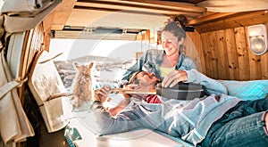 Hippie couple amd dog traveling together on vintage van transport at sunset - Life inspiration concept with guy and girl
