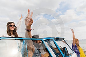 Hippie friends at minivan car showing peace sign