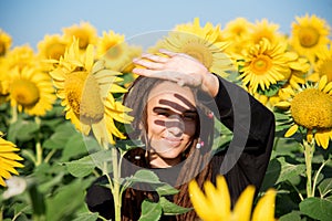 Hippie girl hiding from sunlight in a field with sunflowers