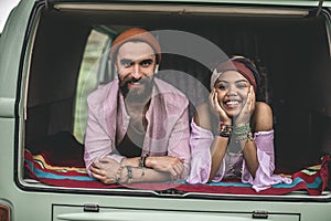 Hippie man and woman laying in retro van trunk