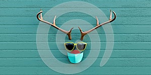Hippie style reindeer with fluffy nose, big yellow sunglasses and face mask, Christmas card template, distressed turqoise planks photo