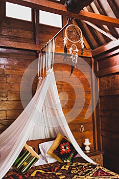 Hippie style wooden room with traditional bed, baldachin and dreamcatcher photo