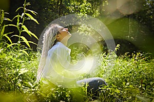 Hippy girl enjoys life in a forest on a sunny spring or summer day. Woman in green nature landscape