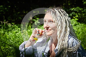 Hippy girl enjoys life in a forest on a sunny spring or summer day. Woman in green nature landscape