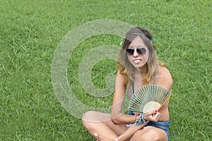 Hippy girl sitting grass holding fan