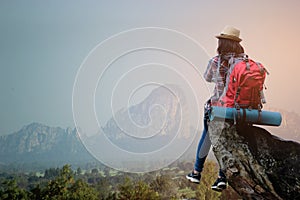 Hipster asian young girl with backpack enjoying sunset on peak mountain. Travel Lifestyle adventure concept