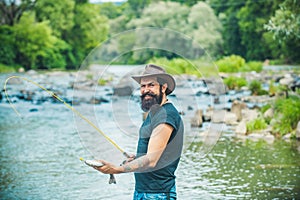 Hipster bearded man catching trout fish. Fisherman caught a fish. Man fishing on river.