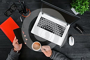 Hipster black wooden desktop top view, male hands typing on a laptop