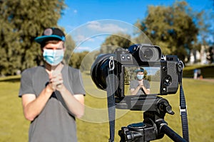 A hipster blogger in a medical mask is blogging on camera. Online communication, consultations, training, business. Distance