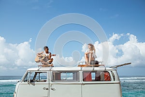 Hipster boy playing guitar with girlfriend on top of retro style