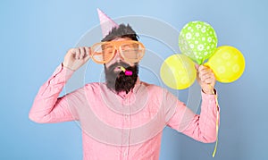 Hipster with bushy beard celebrating birthday. Bearded man posing in birthday cap with enormous glasses and bright