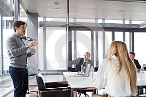 Hipster business man holding coffee cup and presenting the project photo