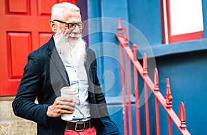 Hipster business man walking with takeaway cup of coffee wall background - Trendy old person wearing casual fashion clothes