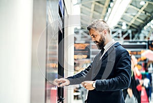 Hipster businessman buying a ticket in a machine on subway station.