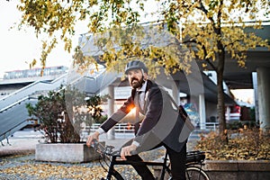 Hipster businessman commuter with electric bicycle traveling home from work in city.