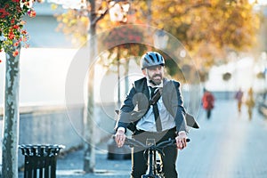 Hipster businessman commuter with electric bicycle traveling home from work in city.